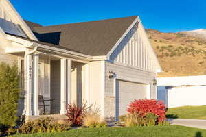 View of side of home featuring covered porch, board and batten siding, a shingled roof, and an attached garage
