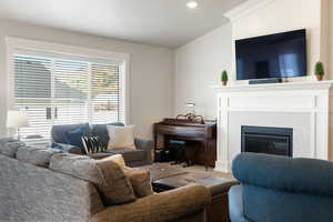 Carpeted living area with a glass covered fireplace and recessed lighting