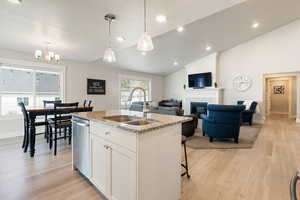 Kitchen featuring recessed lighting, white cabinetry, an island with sink, open floor plan, and light wood-style flooring