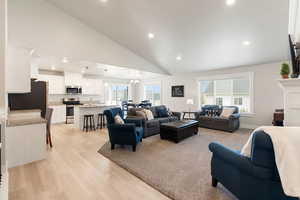 Living room featuring recessed lighting, a chandelier, light wood-style floors, high vaulted ceiling, and a fireplace