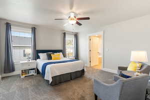 Carpeted bedroom with connected bathroom and a ceiling fan