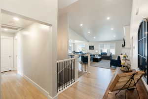 Hall featuring an upstairs landing, recessed lighting, light wood-style floors, and high vaulted ceiling