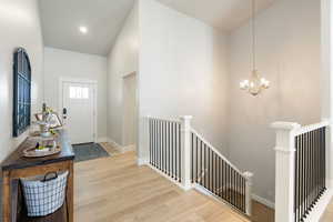 Entrance foyer featuring light wood-style flooring, a chandelier, and a high ceiling