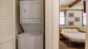 Laundry room featuring stacked washing machine and dryer and carpet flooring