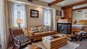 Carpeted living room featuring beamed ceiling and a tiled fireplace
