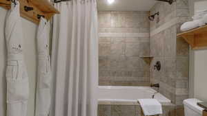 Full bath featuring tiled shower / bath and toilet