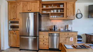 Kitchen with stainless steel appliances, open shelves, tasteful backsplash, dark stone countertops, and light tile patterned flooring