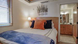 Tiled bedroom featuring ensuite bath