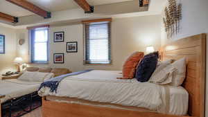 Bedroom featuring beamed ceiling and multiple windows