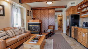 Living room with beam ceiling, a multi sided fireplace, and light tile patterned floors