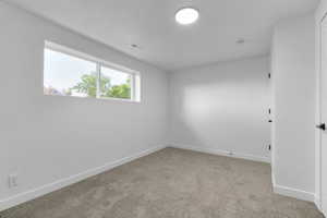 Spare room featuring light colored carpet and baseboards