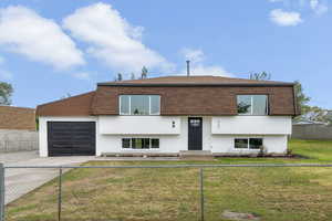 View of front facade with concrete driveway, mansard roof, and an attached garage