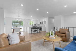 Living area featuring light wood-type flooring, recessed lighting, and a chandelier