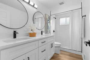 Bathroom with double vanity, a shower stall, and light wood finished floors