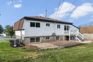 Rear view of house featuring a deck with mountain view, a patio, and a shingled roof