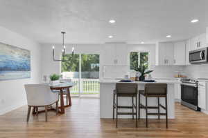 Kitchen with appliances with stainless steel finishes, a kitchen island, tasteful backsplash, a kitchen breakfast bar, and white cabinetry