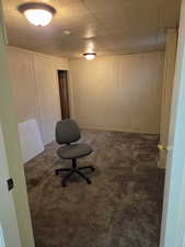 Unfurnished office featuring wood walls and dark colored carpet