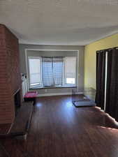 Unfurnished living room featuring a textured ceiling, dark wood-style flooring, and a fireplace