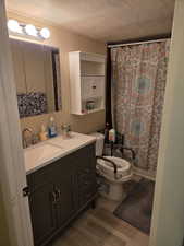 Full bath with a textured ceiling, dark wood-type flooring, vanity, and curtained shower