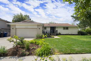 Ranch-style home with driveway, an attached garage, a front yard, brick siding, and a shingled roof