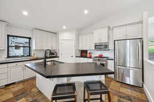 Kitchen featuring plenty of natural light, appliances with stainless steel finishes, a kitchen breakfast bar, white cabinetry, and recessed lighting