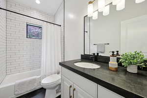 Full bathroom with shower / bathtub combination with curtain, vanity, and dark tile patterned floors