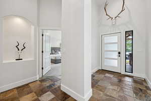 Foyer entrance with a towering ceiling and stone tile floors