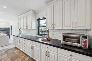 Kitchen featuring open floor plan, decorative backsplash, white cabinets, a textured ceiling, and recessed lighting