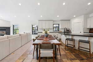 Dining room with recessed lighting, healthy amount of natural light, a textured ceiling, stone tile floors, and a fireplace
