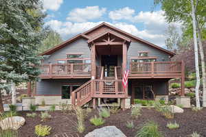Rustic home featuring a deck, stairway, and stone siding