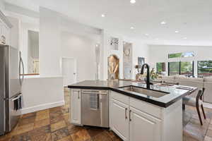 Kitchen with white cabinetry, open floor plan, stainless steel appliances, recessed lighting, and an island with sink