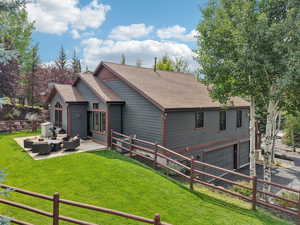 Back of property featuring a shingled roof, an attached garage, a patio area, and asphalt driveway