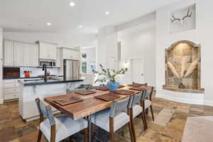Dining area with stone tile flooring, recessed lighting, and high vaulted ceiling