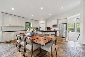 Dining area featuring recessed lighting, vaulted ceiling, and stone tile floors