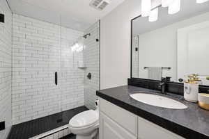 Full bath featuring vanity, a shower stall, and a textured ceiling