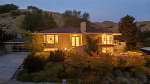 Rear view of house featuring a balcony, driveway, a mountain view, and stucco siding