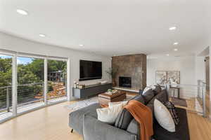 Living room featuring light wood-style floors, recessed lighting, and a large fireplace