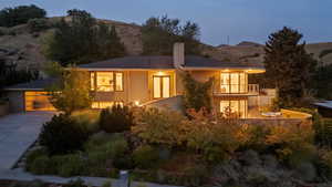 Rear view of house featuring a balcony, a mountain view, driveway, and a chimney