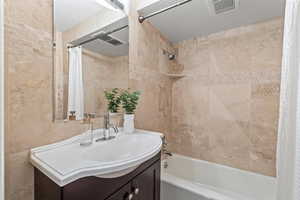 Bathroom with shower / bath combo, vanity, and tile walls