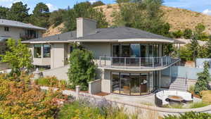 Rear view of property with an outdoor fire pit, stucco siding, a chimney, a balcony, and a patio