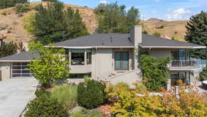 View of front facade featuring a balcony, stucco siding, a chimney, and driveway