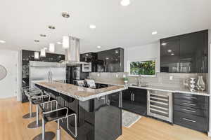 Kitchen with dark cabinets, modern cabinets, a kitchen breakfast bar, pendant lighting, and backsplash
