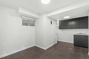 Finished below grade area with dark tile patterned flooring and baseboards