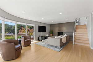 Living room with stairs, recessed lighting, and light wood-style floors