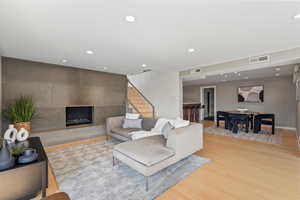 Living room with light wood-type flooring, recessed lighting, a fireplace, and stairway