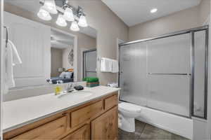 Full bathroom featuring shower / bath combination with glass door, vanity, ensuite bathroom, and light tile patterned flooring