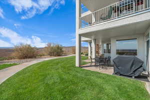 View of green lawn featuring a patio area and a balcony