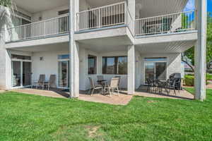 Rear view of property featuring a patio, stucco siding, a lawn, and a balcony