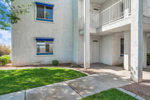 Property entrance featuring stucco siding and a yard
