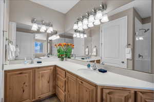 Full bath featuring double vanity, a tile shower, and tile patterned flooring
